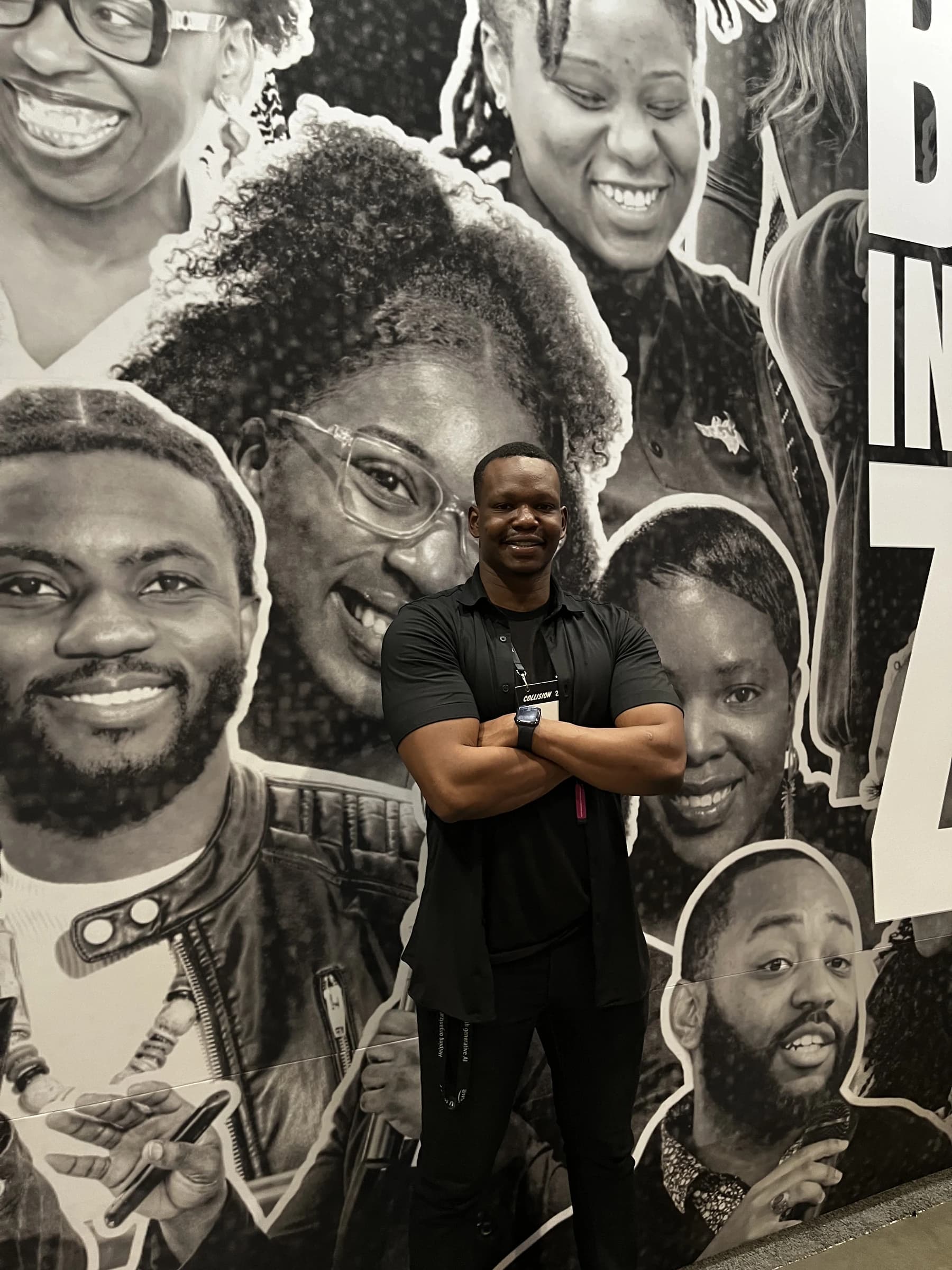 Dico in front of a Black-in-Tech mural at a tech event