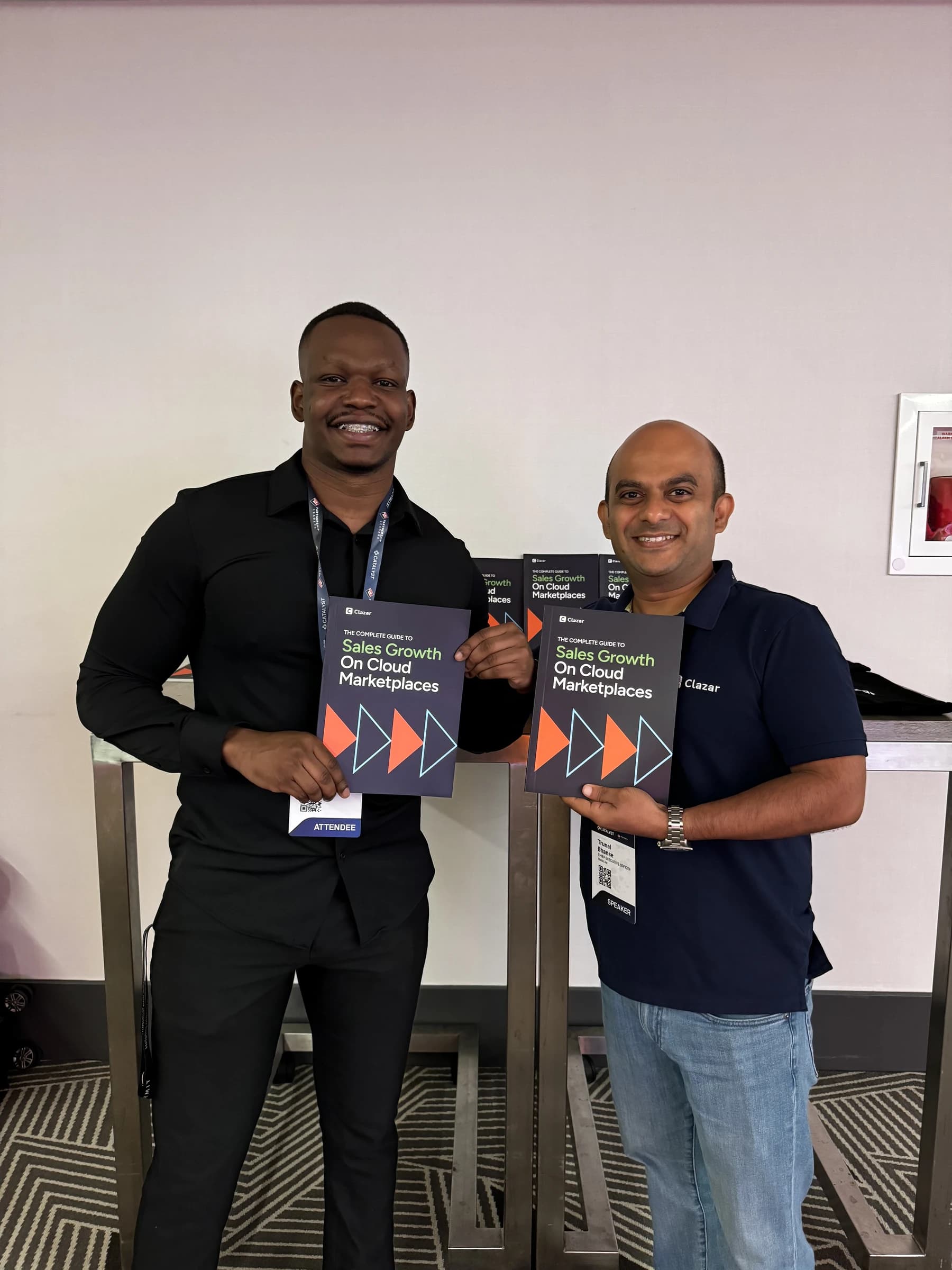 Dico with a partner at a Cloud Marketplaces summit holding the Clazar guide