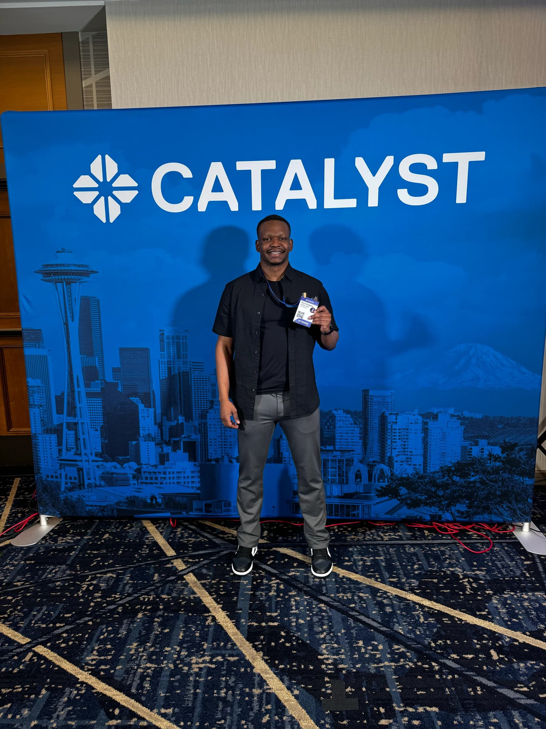 Dico in front of Catalyst step-and-repeat with Seattle skyline backdrop